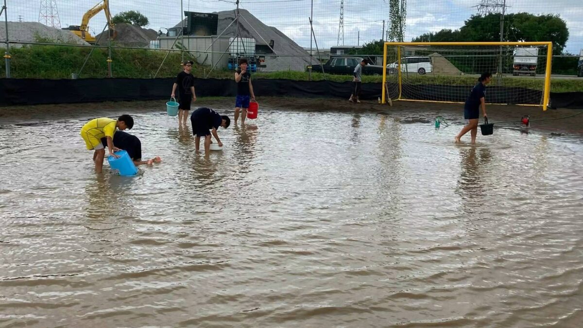 ビーチコートで水をくみ出す選手と保護者